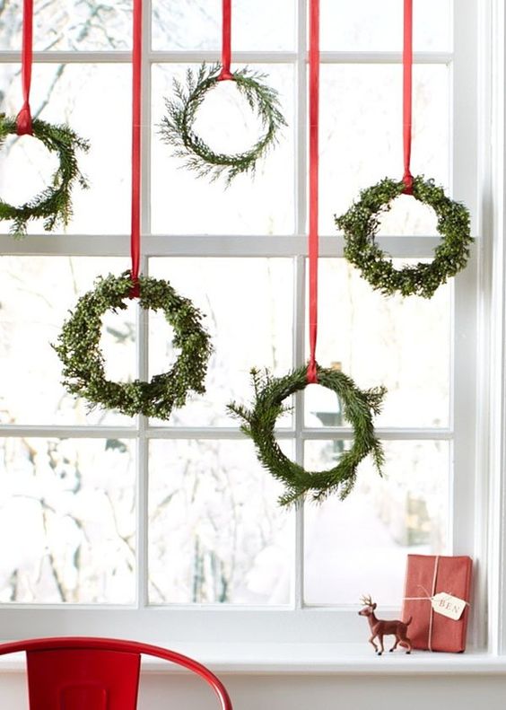 Christmas Decoration Inspiration - green wreaths hanging on red ribbons, so pretty!