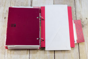 DIY Upcycled Christmas Card Books - I glue an envelope to red cardstock for each double-sided letter. | https://www.roseclearfield.com
