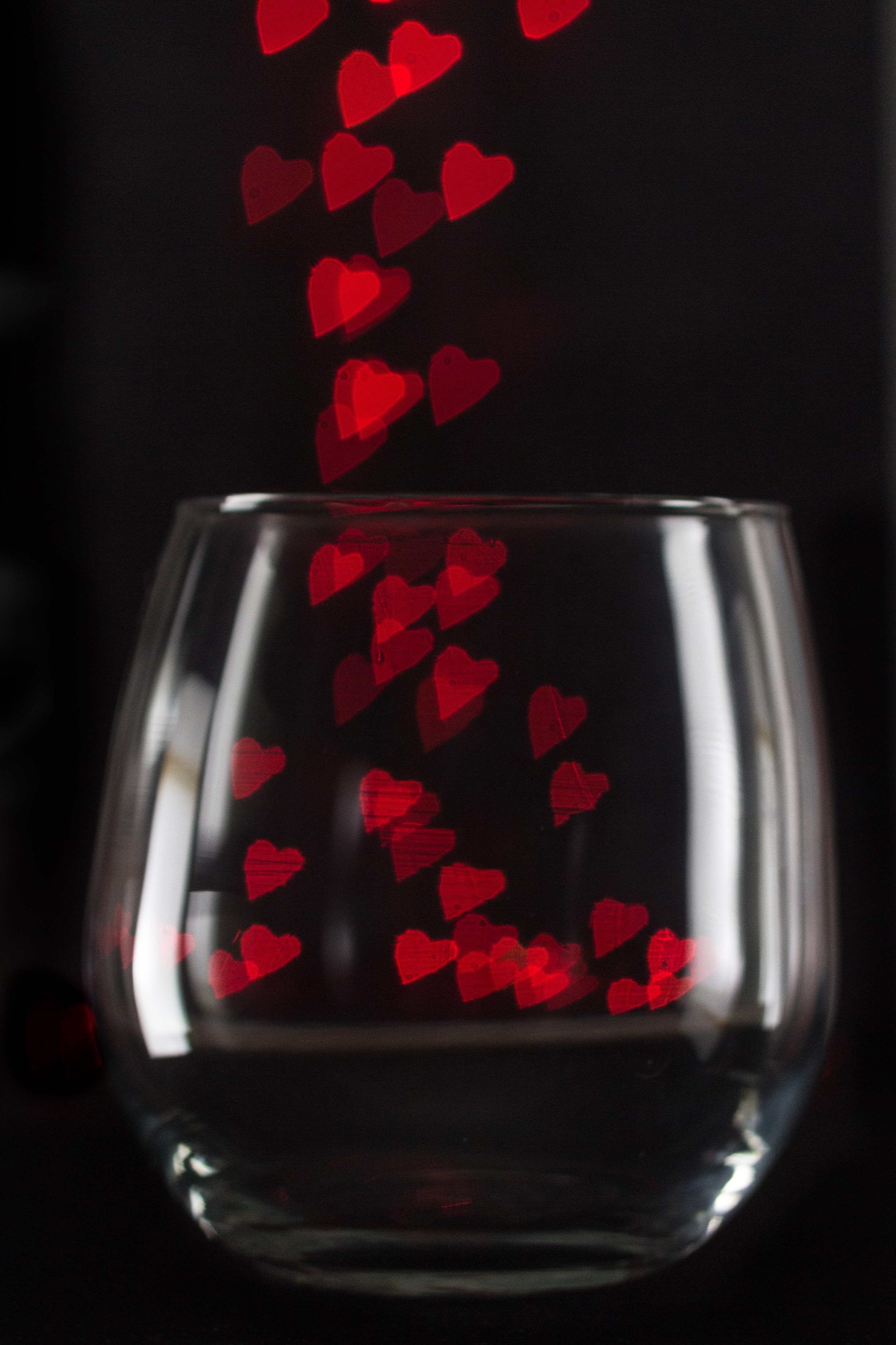 Clear stemless wine glass with red heart bokeh. | https://www.roseclearfield.com