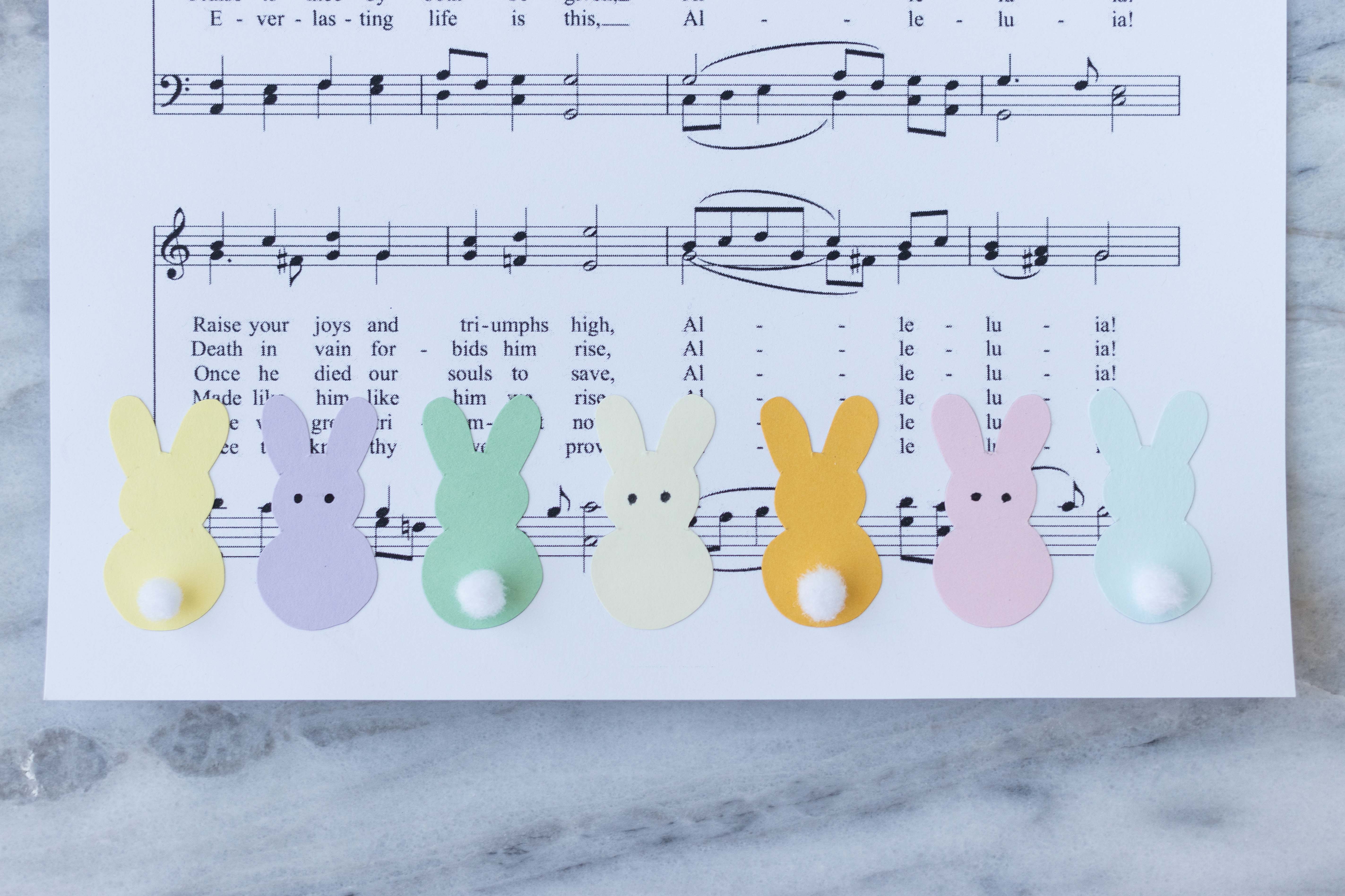 DIY Easter sheet music wall decor in progress! Pom pom tails and eyes add a fun touch to the bunnies. #Easter #DIY #sheetmusic | https://www.roseclearfield.com