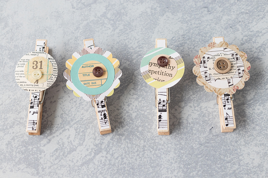 Sheet music clothespin magnets with homemade scrapbook embellishments. Such a pretty, simple touch to create one of a kind home decor! #DIY #sheetmusic #clothespins #scrapbookembellishments | https://www.roseclearfield.com