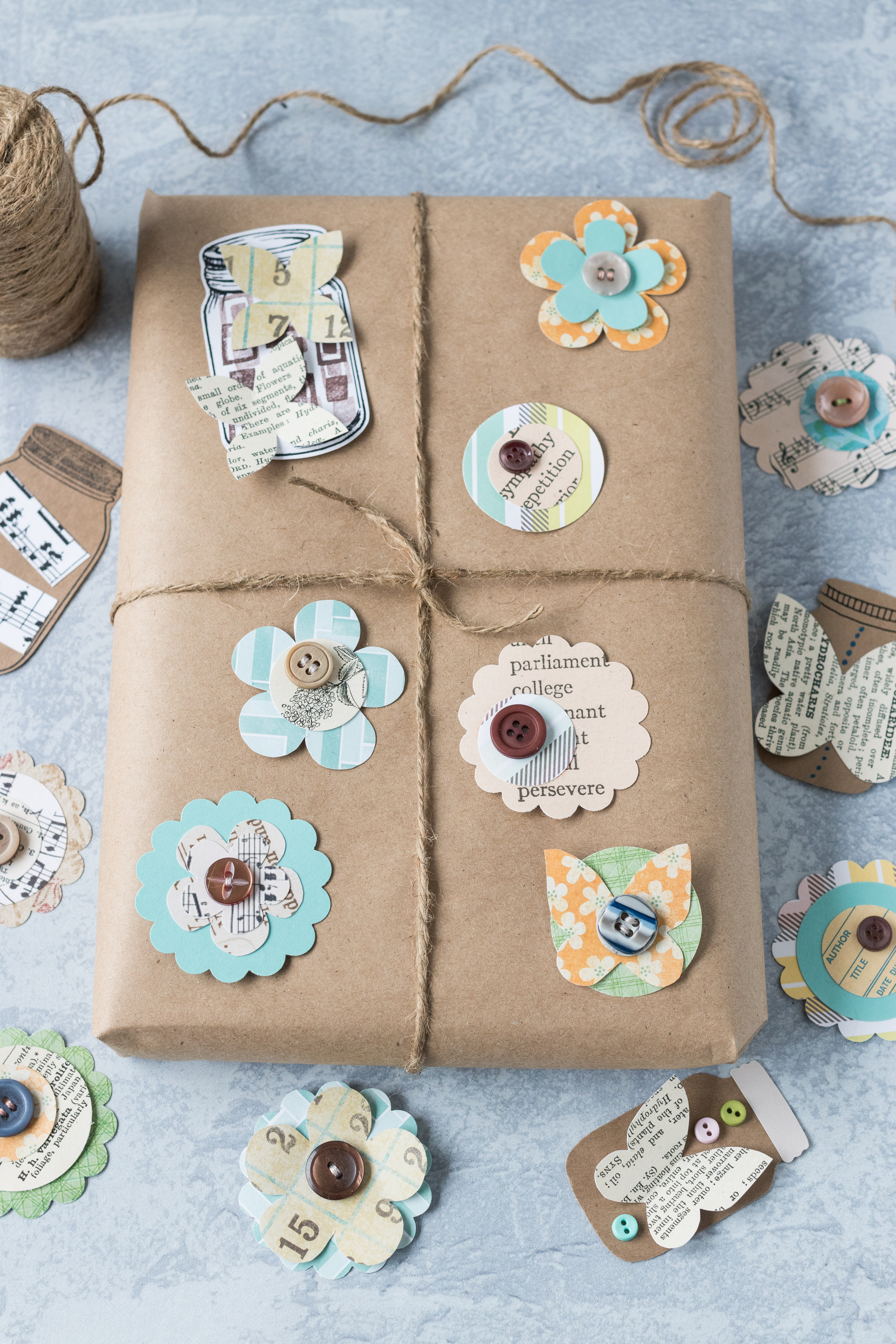 Brown kraft wrapped package decorated with DIY scrapbook embellishments. Quick, custom gift wrap! #DIY #giftwrapidea #kraftpaper #scrapbookembellishments | https://www.roseclearfield.com