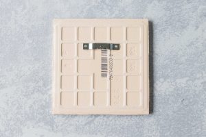 A sawtooth hanger, attached with E-6000 adhesive, is perfect for hanging decorated ceramic tiles. #DIY #sawtoothhanger #ceramictiles | https://www.roseclearfield.com