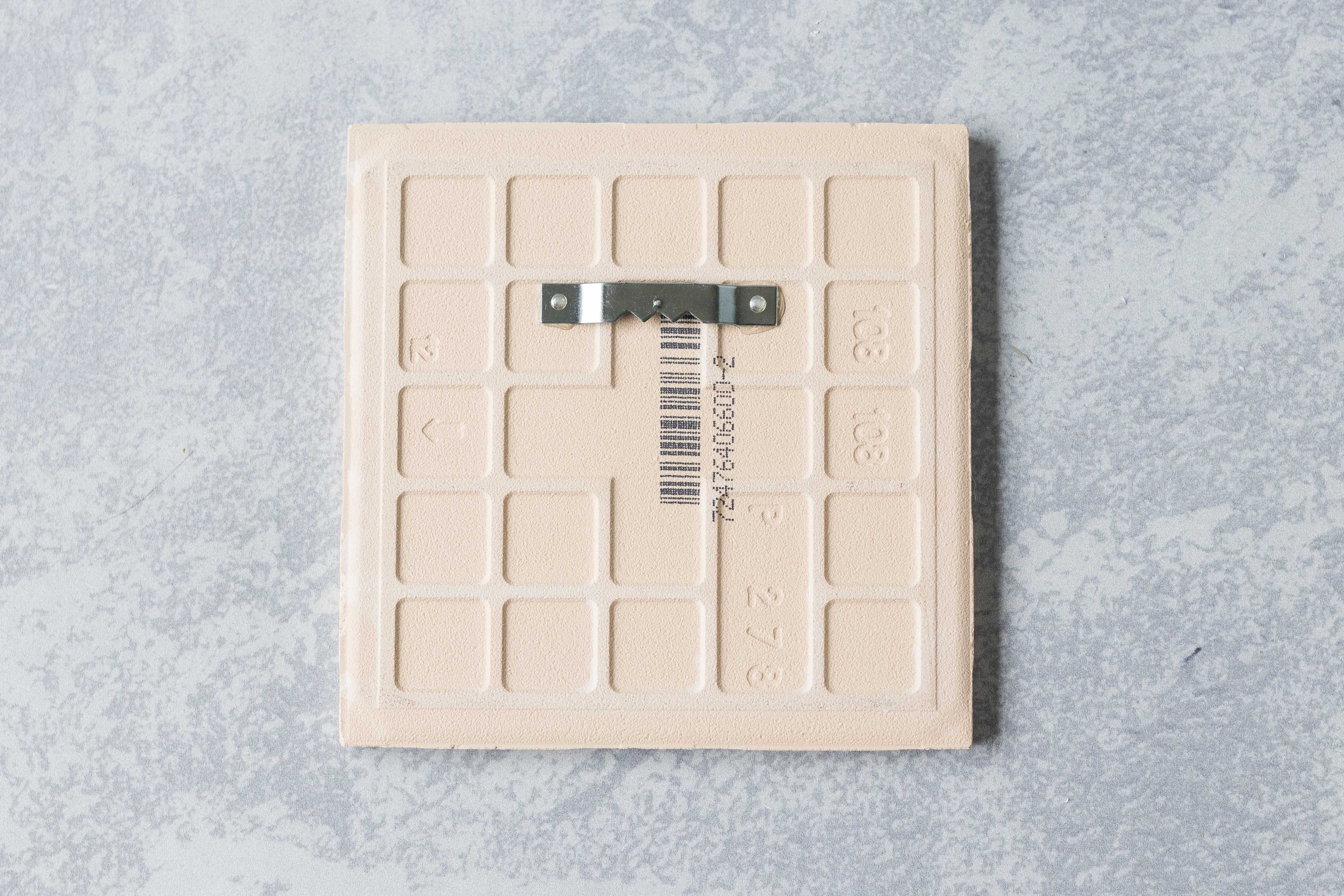 A sawtooth hanger, attached with E-6000 adhesive, is perfect for hanging decorated ceramic tiles. #DIY #sawtoothhanger #ceramictiles | https://www.roseclearfield.com